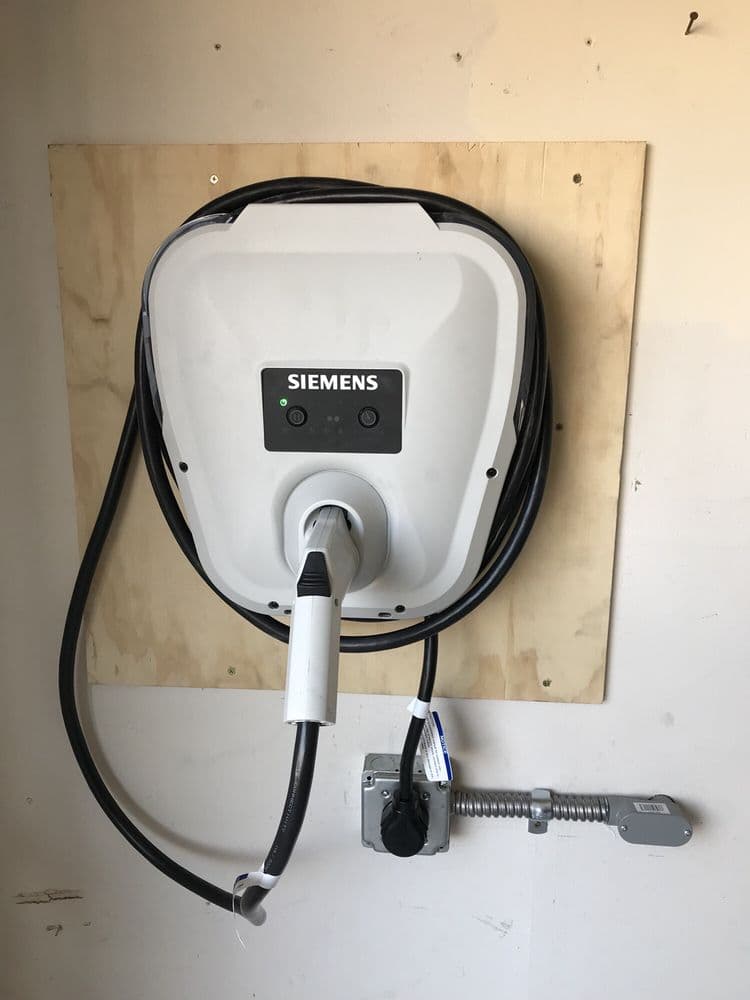 Siemens electric vehicle charging station mounted on a wooden wall.