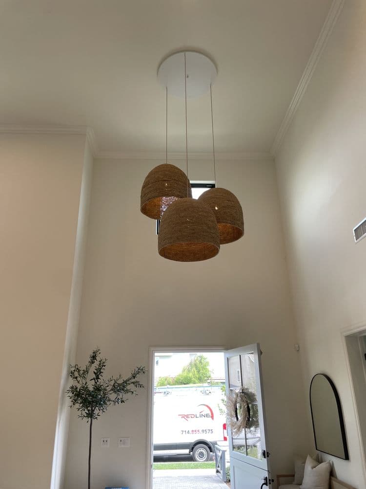 Modern living room with three woven pendant lights hanging from a high ceiling.