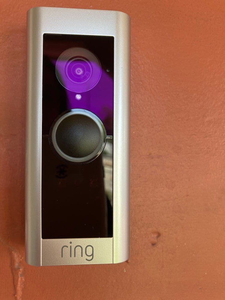 Ring video doorbell mounted on a wall with camera lens and button clearly visible.