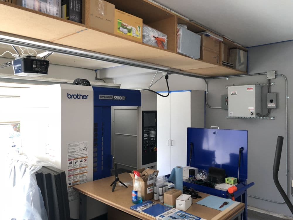 Brother S500X1 CNC machine in a garage workshop with organized overhead storage.