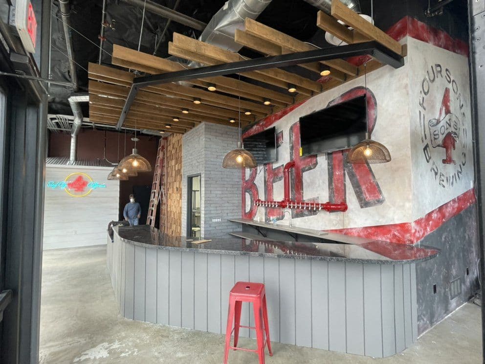 Modern bar interior featuring a striking beer-themed wall, pendant lights, and sleek finishes.