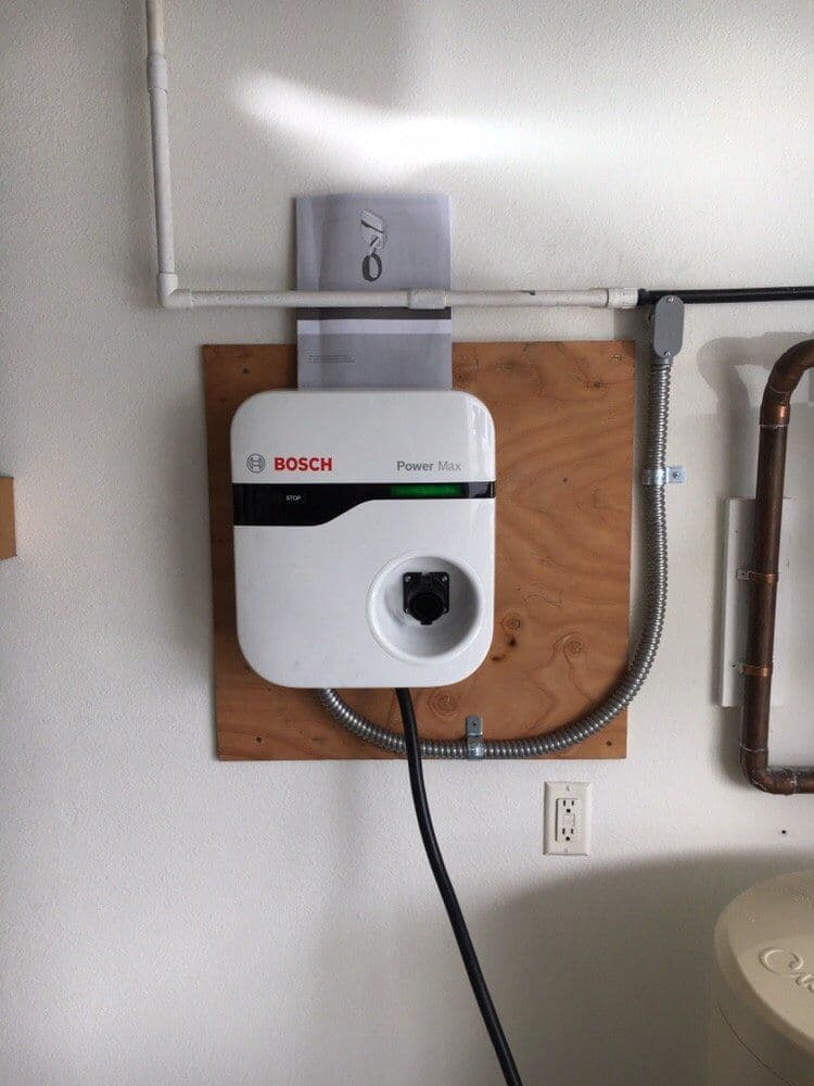 Bosch Power Max electric water heater mounted on wall with installation manual above it.