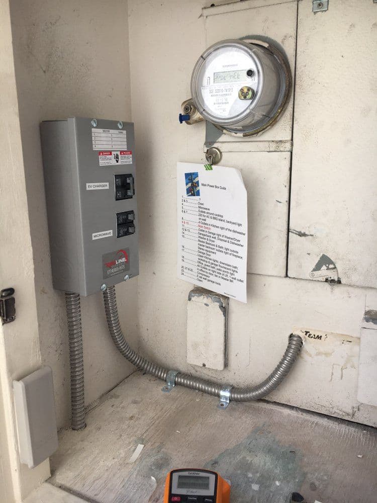 Electrical panel and gas meter installation in a utility room with safety instructions visible.