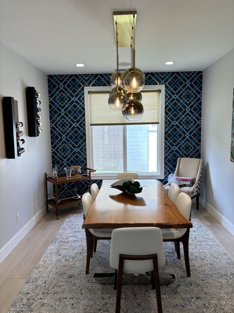 Modern dining room featuring a wooden table, stylish chairs, unique pendant light, and patterned wall.