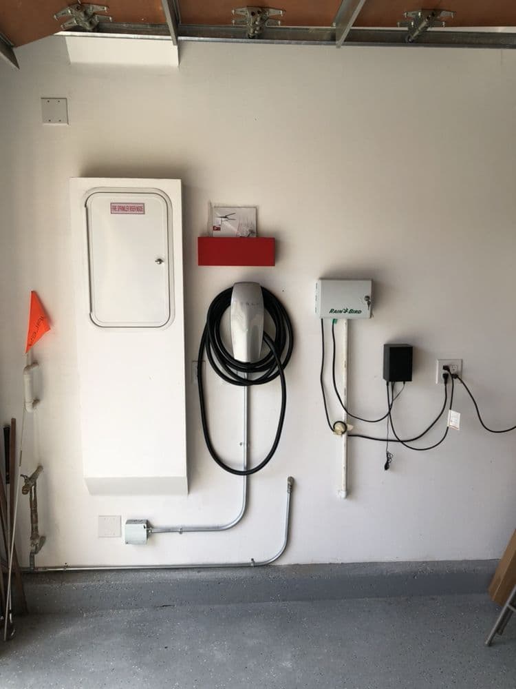 Electric vehicle charging station installed in a garage featuring wall-mounted equipment.