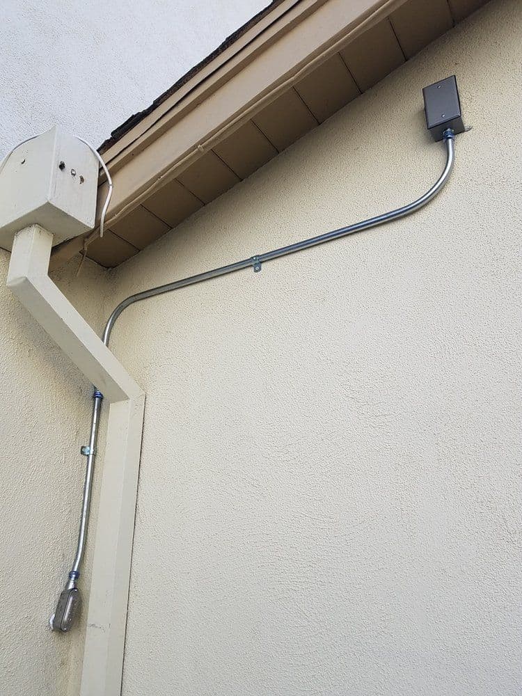 Metal conduit and electrical box installed on a residential exterior wall.