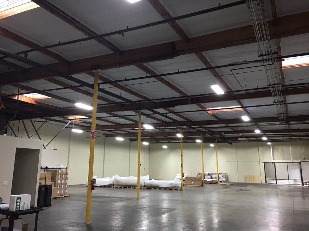 Spacious warehouse interior with high ceilings, yellow support columns, and efficient lighting.
