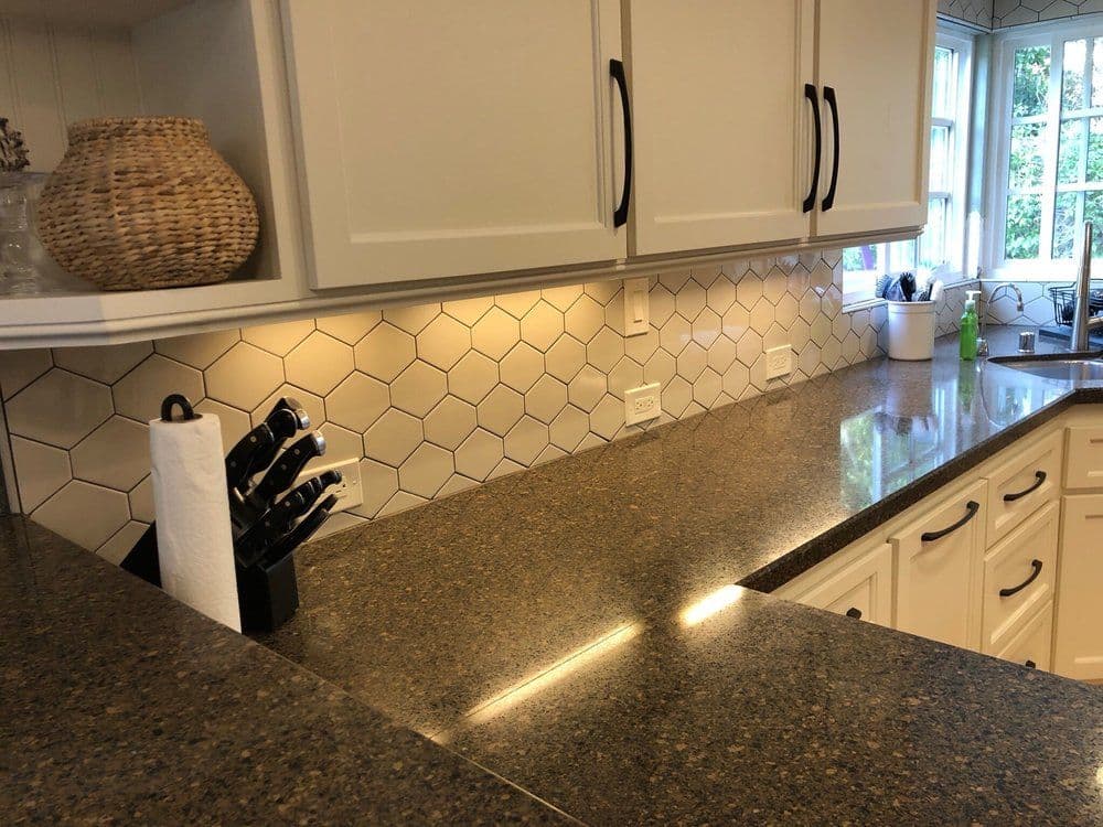 Modern kitchen with hexagon tile backsplash, sleek countertops, and stylish knife block.