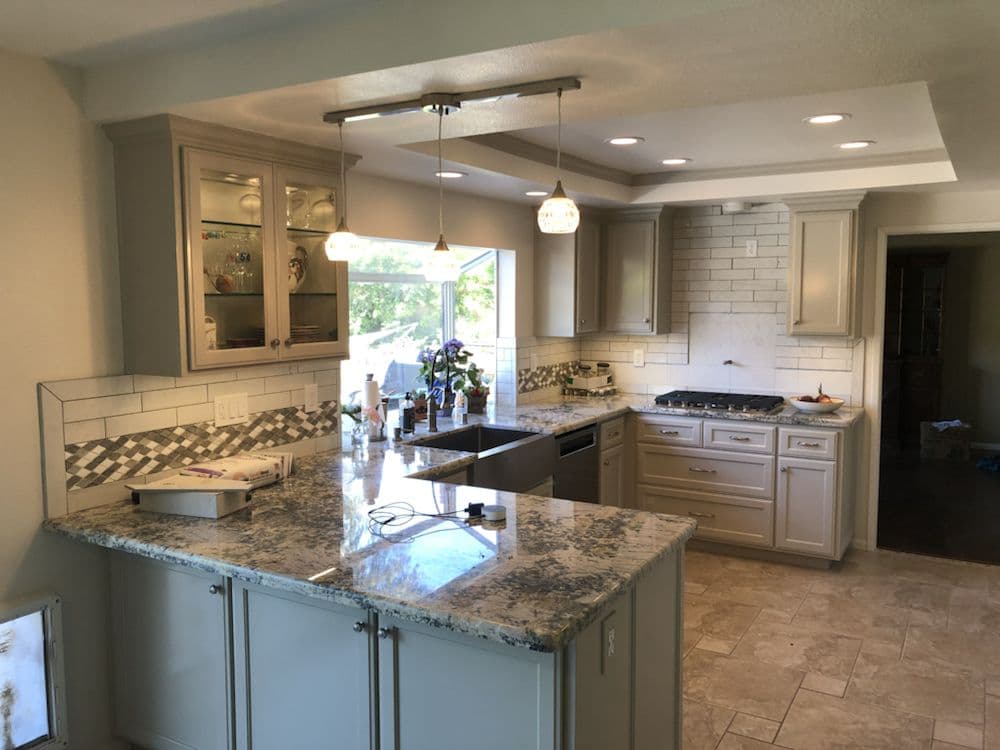 Modern kitchen with gray cabinets, granite countertops, and stainless steel appliances.